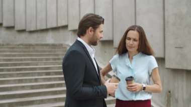 Sokakta konuşmak için elinde kahve olan menajerler. Arkadaşlar dışarıda gülüyor.