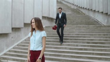 Kadın akıllı saati kontrol ediyor. İş adamı iş kadınına gül veriyor