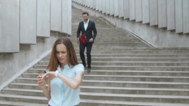 İş kadını caddedeki akıllı saati kontrol ediyor. Çiçek veren adam kadın.