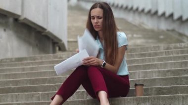 Kötü mali istatistiklere bakan bir iş kadını. Müdür merdivenlerde oturuyor.