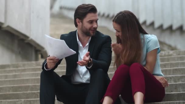 Joyful business man and business woman discussing results on documents in city — Stock Video