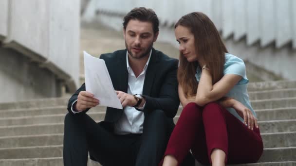 Tired business man and business woman looking at business papers on street — Stock Video