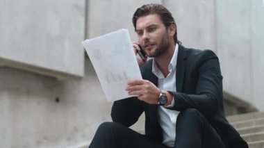 Sokakta akıllı telefondan konuşan bir iş adamı. İş adamı başarıyı kutluyor