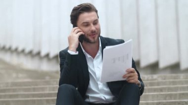 İş adamı akıllı telefondan konuşuyor. Yönetici analiz şemaları