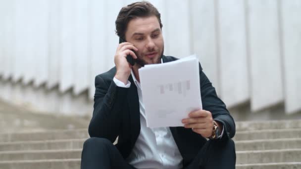 Hombre de negocios hablando con el cliente en el teléfono inteligente en la calle. Hombre mirando gráficos — Vídeos de Stock