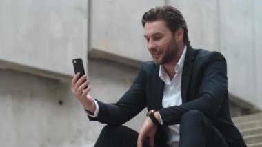 İş adamı telefon kamerasına el sallıyor. Çevrimiçi iş görüşmesi yapan yönetici
