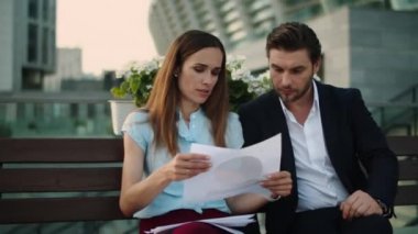 İş adamı ve işkadını şehir sokaklarında belgeleri tartışıyor.
