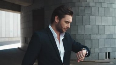 İş adamı caddedeki kol saatini kontrol ediyor. Adam ortağını bekliyor.