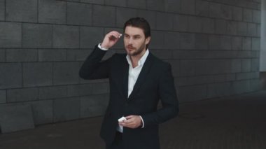 İş adamı sokakta kablosuz kulaklık takıyor. Bluetooth kulaklık kullanan bir adam.
