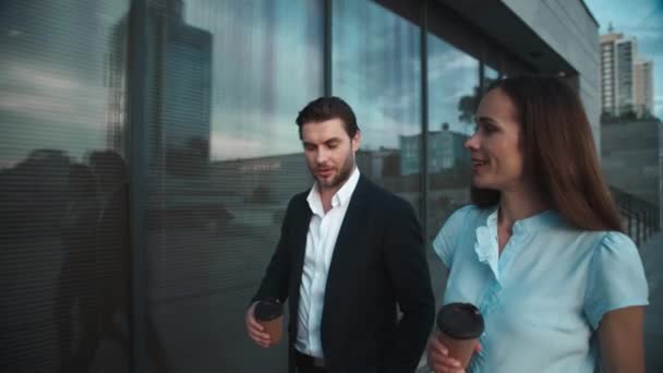 İş adamı ve iş kadını şehirde yürüyor. İş arkadaşları kahve içiyor. — Stok video