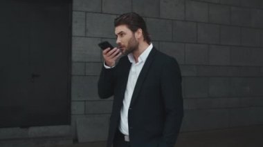 Ciddi bir iş adamı dışarıdaki akıllı telefondan sesli mesaj kaydediyor.