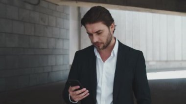 Heyecanlı iş adamının portresi Şehir Caddesinde akıllı telefondan iyi haberler okuyor.
