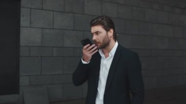 Şehirdeki iş adamı hoparlörden konuşuyor. Sesli mesaj kaydeden adam