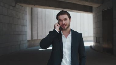 İş adamı şehirde cep telefonuyla konuşuyor. Erkek profesyonel başarıyı kutluyor