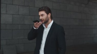 Şaşkın iş adamı şehir caddesindeki akıllı telefondan sesli mesaj kaydediyor.