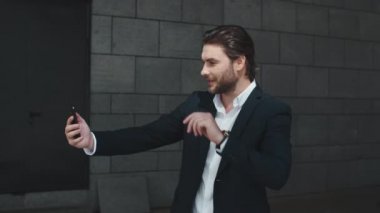 İş adamı sokakta kameraya el sallıyor. Girişimci görüntülü konuşma yapıyor