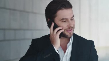 İş adamı sokakta cep telefonuyla konuşuyor. Şehirdeki akıllı telefondan arayan adam.