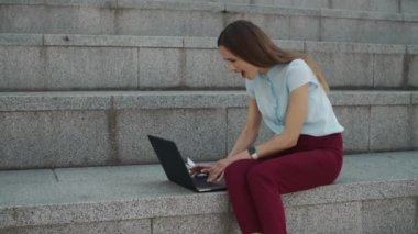 İş kadını laptoptan iyi haberler okuyor. Şehirde başarıyı kutlayan işçiler