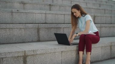 İş kadını dışarıda dizüstü bilgisayarla çalışıyor. Sokakta dizüstü bilgisayarda yönetici daktilo