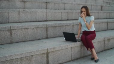 Şehirde dizüstü bilgisayarda çalışan bir iş kadını. Yönetici sokağa çıkmak için kahve içiyor.