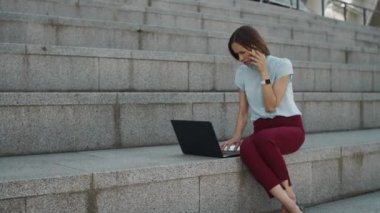 İş kadını akıllı telefondan konuşuyor. Dizüstü bilgisayarı kullanarak profesyonelce.