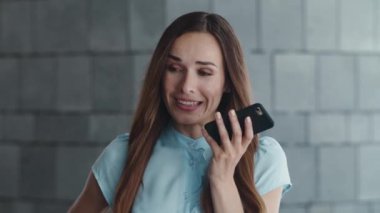 Gülümseyen iş kadını şehirdeki akıllı telefondan sesli mesaj kaydediyor.