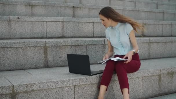 Geschäftsfrau, die auf der Straße mit Geschäftspapieren arbeitet. Mitarbeiter tippt auf Laptop — Stockvideo