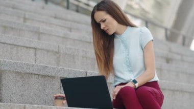 Şehirde dizüstü bilgisayarda çalışan bir iş kadını. Çalışan dışarıda iş gazeteleri okuyor.