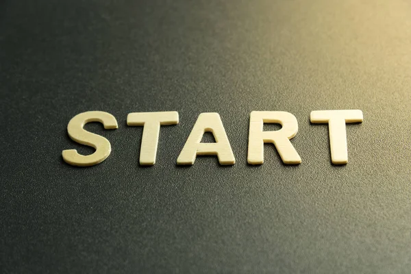 Kelimenin ahşap harfi siyah arkaplanda başlar