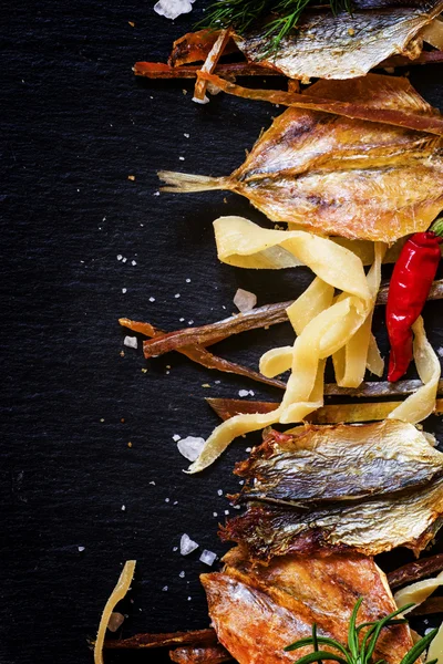 Hintergrund ungesunder Ernährung: Trockenfisch, geräucherter Tintenfisch, Gewürze. — Stockfoto