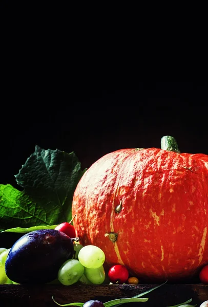 Herbst Hintergrund, orange Kürbisse, Pflaumen, Feigen, Trauben, Weißdorn und Sanddorn — Stockfoto