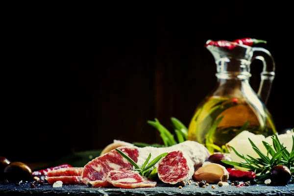 Rántott olasz szalámi rozmaringgal, fűszerekkel, olajbogyókkal és olajjal. — Stock Fotó
