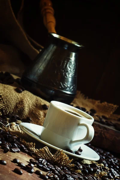 White cup of black coffee with foam, Turkish coffee maker on the old wooden table — 스톡 사진