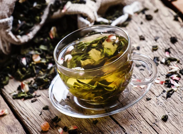 Чашка зеленого чая с лепестками цветов и фруктами — стоковое фото