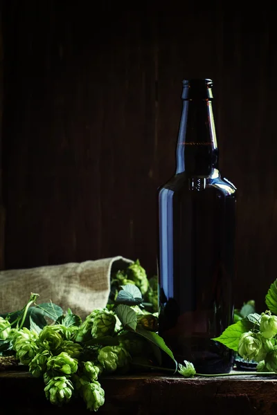 Cerveza con lúpulo, fondo de madera oscura — Foto de Stock