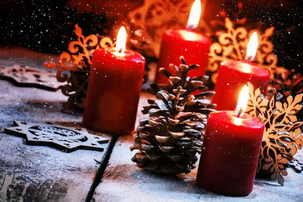 Burning red candles and pine cones with snowflakes — Stock fotografie