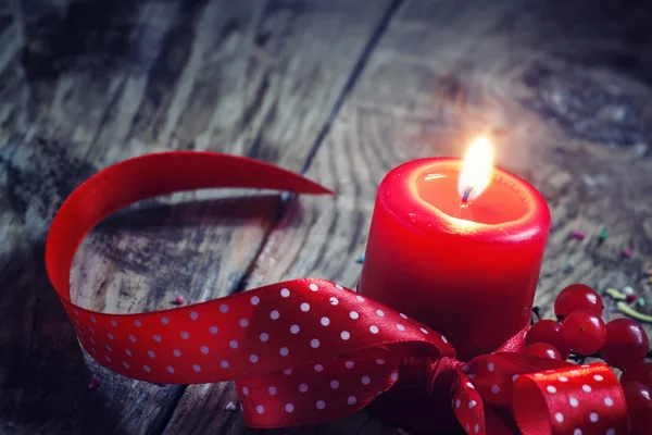 Burning candle with a red polka dot ribbon and berries — Stock Photo, Image
