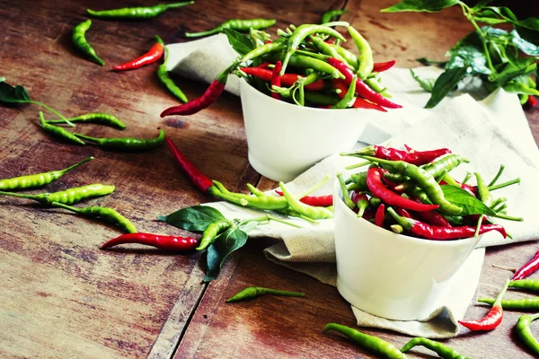 Red and green chili peppers in white bowls — Stockfoto