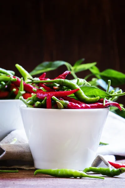 Red and green chili peppers in white bowls — ストック写真