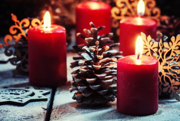 Burning red candles and pine cones with snowflakes — Stock fotografie