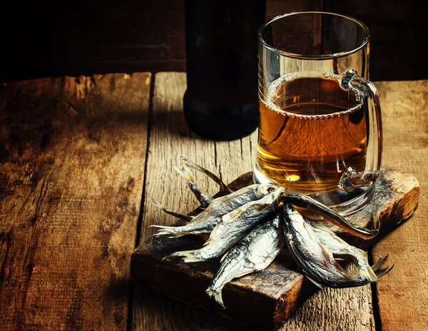 Beer and fish, dark wood background 