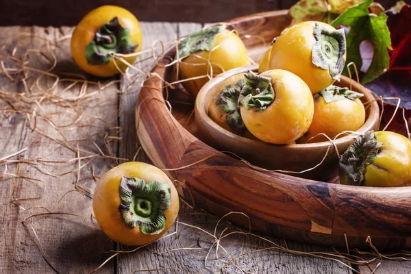 Persimmons, old wooden background — Stock Photo, Image
