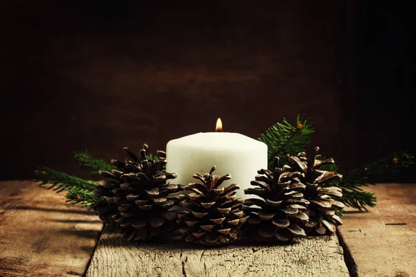 Рождественская или новогодняя композиция с горящими свечами и сосновыми шишками — стоковое фото