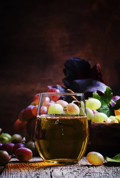Grape juice in glass and berries with leaves — Stock Photo, Image