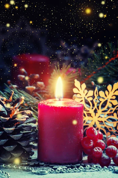 Красная горящая свеча с шишками и снежинками — стоковое фото