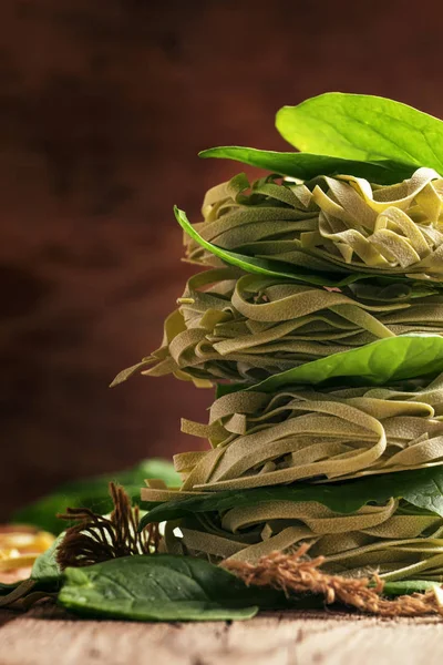 Dried pasta with fresh spinach, old wooden background — Stock Photo, Image