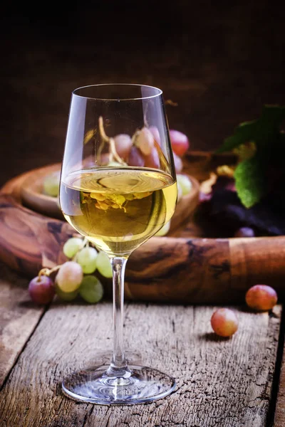 Белое вино в стакане с осенним виноградом — стоковое фото