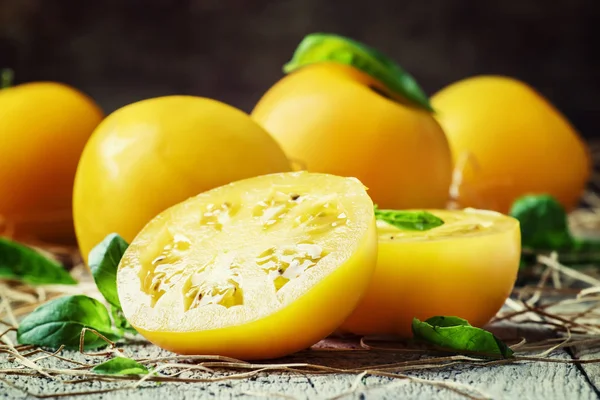 Cut large yellow tomatoes and green leaves of basil — Stock Photo, Image