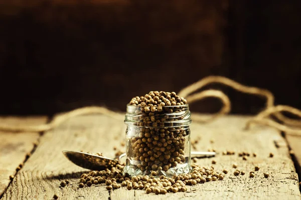 Koriander zaden in een glazen pot, vintage houten achtergrond — Stockfoto