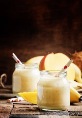 Muz mango smoothie ile Hindistan cevizi bir cam kavanozlar